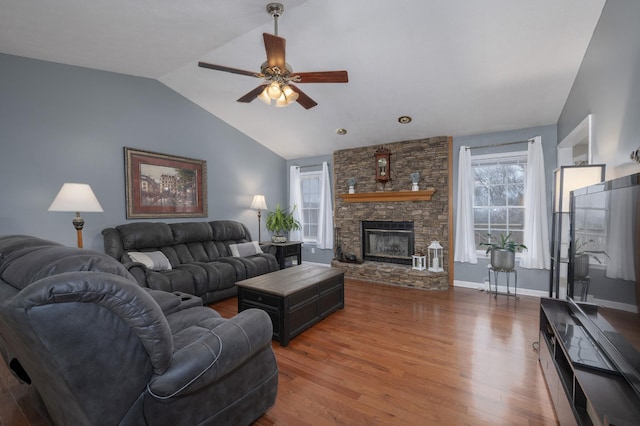 living room featuring vaulted ceiling, a stone fireplace, ceiling fan, and dark hardwood / wood-style floors