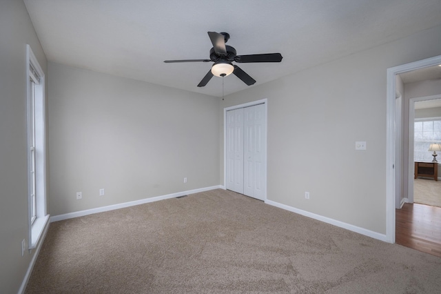 unfurnished bedroom featuring ceiling fan, multiple windows, light carpet, and a closet