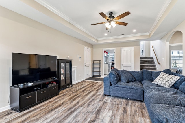 living room featuring a tray ceiling, ceiling fan, hardwood / wood-style floors, and ornamental molding