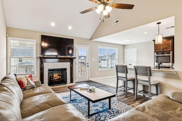 living room featuring a tile fireplace, sink, vaulted ceiling, dark hardwood / wood-style floors, and ceiling fan