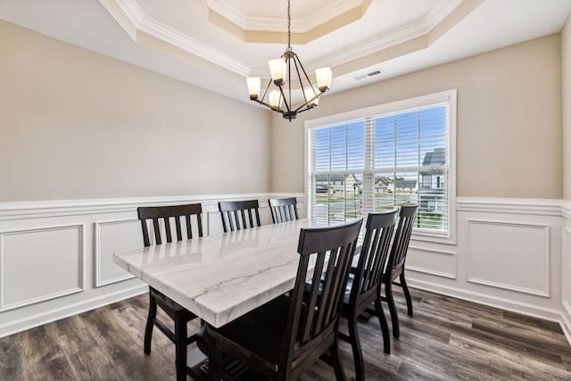 dining space with a raised ceiling, ornamental molding, dark hardwood / wood-style floors, and an inviting chandelier