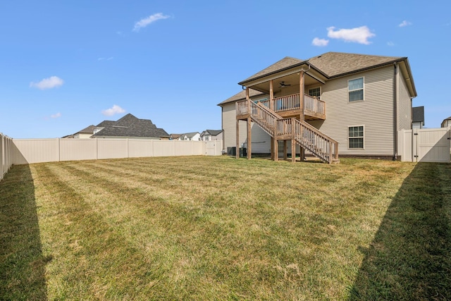 back of property with a deck, ceiling fan, and a lawn