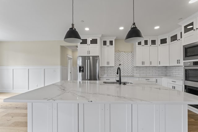 kitchen with decorative light fixtures, stainless steel refrigerator with ice dispenser, and a large island with sink