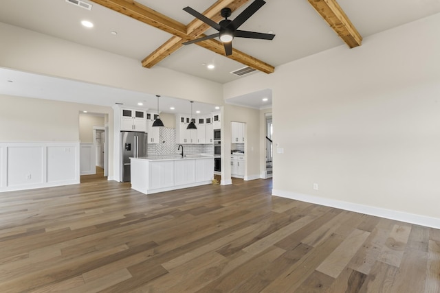 unfurnished living room featuring beamed ceiling, dark hardwood / wood-style flooring, ceiling fan, and sink