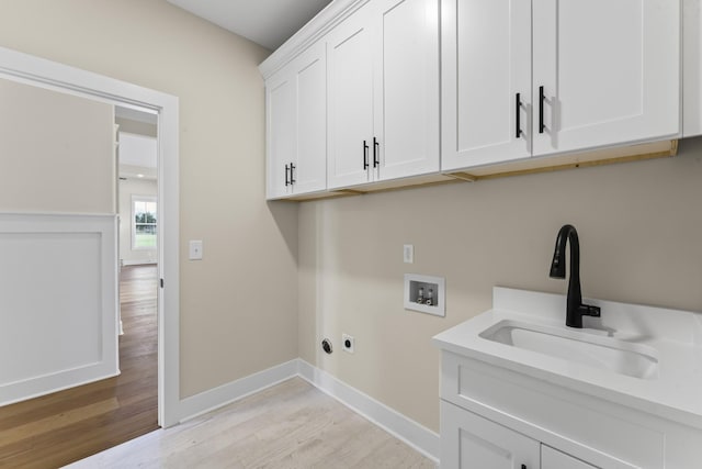 washroom with cabinets, washer hookup, hookup for an electric dryer, sink, and light hardwood / wood-style flooring