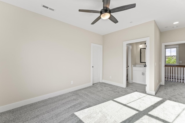 unfurnished bedroom featuring ceiling fan, light carpet, and connected bathroom