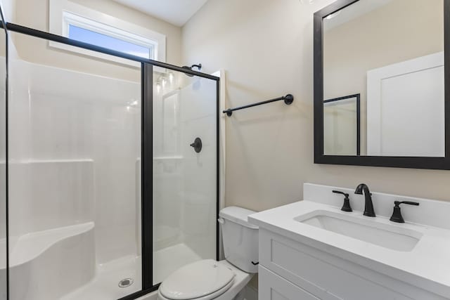 bathroom with vanity, toilet, and a shower with door