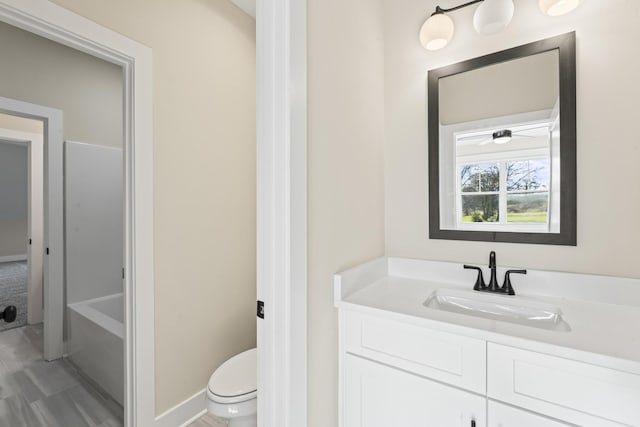 bathroom with vanity, a bath, and toilet