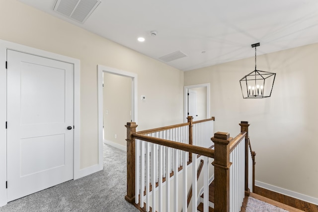 hall featuring carpet and a notable chandelier