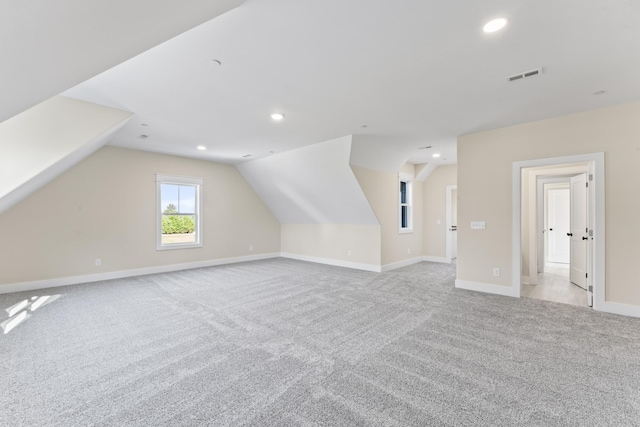 additional living space featuring light colored carpet and lofted ceiling