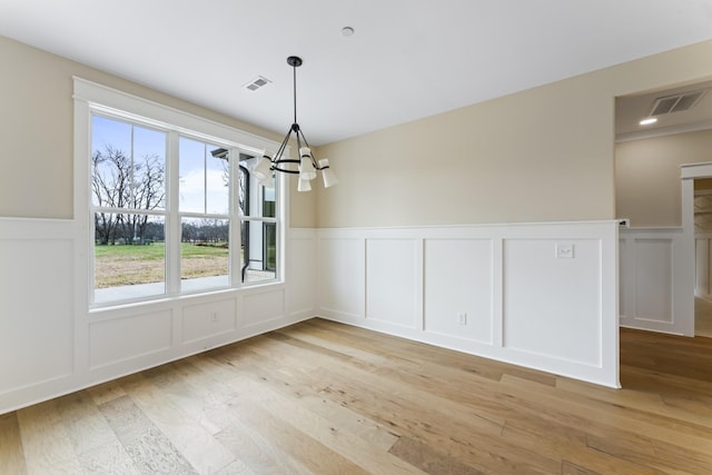 unfurnished dining area with light wood-type flooring and an inviting chandelier