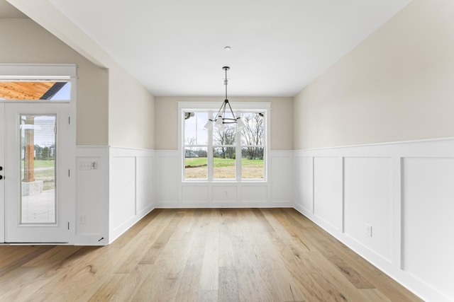 unfurnished dining area featuring light hardwood / wood-style floors and an inviting chandelier