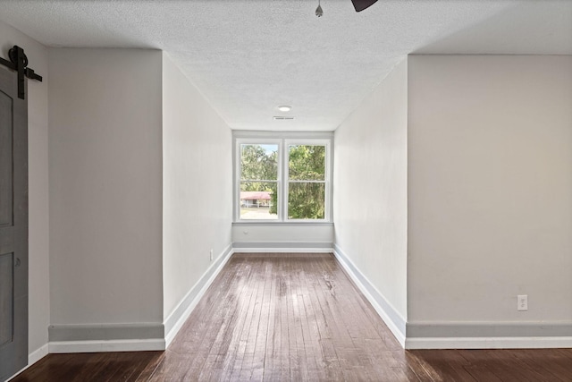 hall with hardwood / wood-style flooring, a barn door, and a textured ceiling