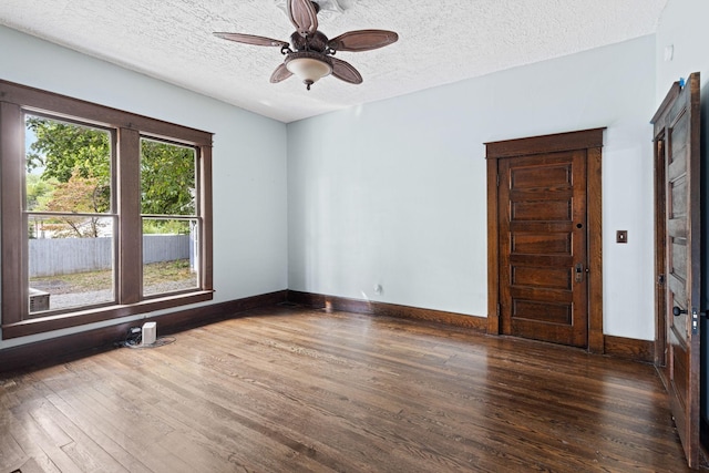 empty room featuring ceiling fan, dark wood-type flooring, and a textured ceiling