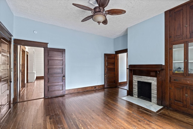 unfurnished living room with wood-type flooring, a textured ceiling, a stone fireplace, and ceiling fan