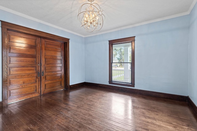 spare room with crown molding, dark wood-type flooring, and a chandelier