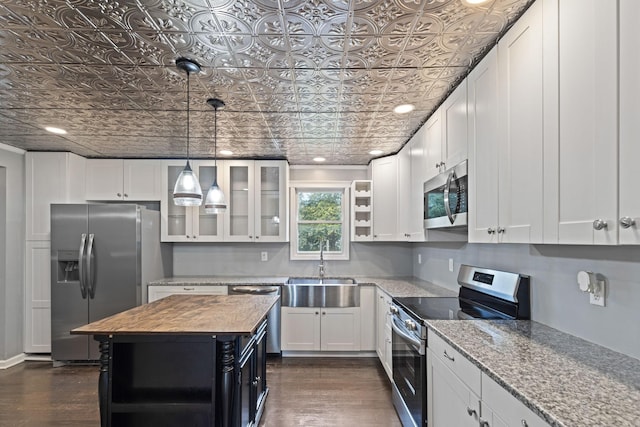 kitchen featuring light stone countertops, stainless steel appliances, a kitchen island, dark wood-type flooring, and white cabinetry