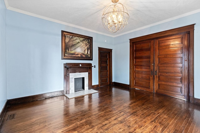 unfurnished living room with dark hardwood / wood-style flooring, ornamental molding, a textured ceiling, a tile fireplace, and a chandelier