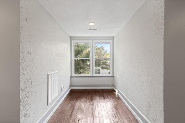 spare room featuring hardwood / wood-style floors and a textured ceiling