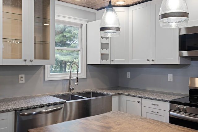 kitchen featuring decorative light fixtures, a wealth of natural light, white cabinetry, and appliances with stainless steel finishes