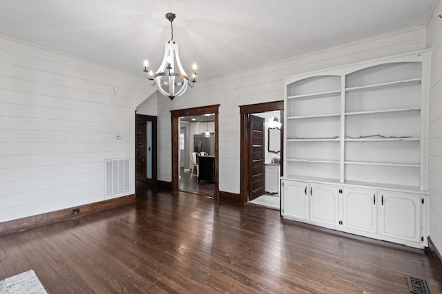 unfurnished dining area with a chandelier, built in features, and dark wood-type flooring