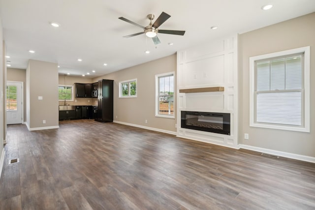 unfurnished living room with dark hardwood / wood-style flooring and ceiling fan