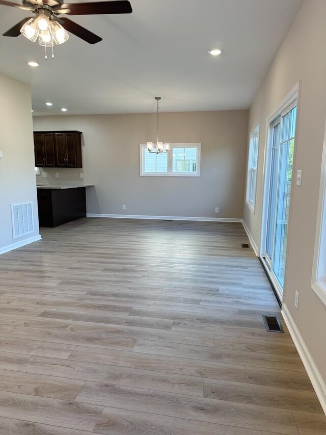 interior space with light hardwood / wood-style floors and ceiling fan with notable chandelier