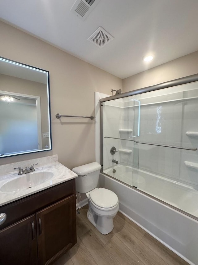 full bathroom with shower / bath combination with glass door, wood-type flooring, vanity, and toilet