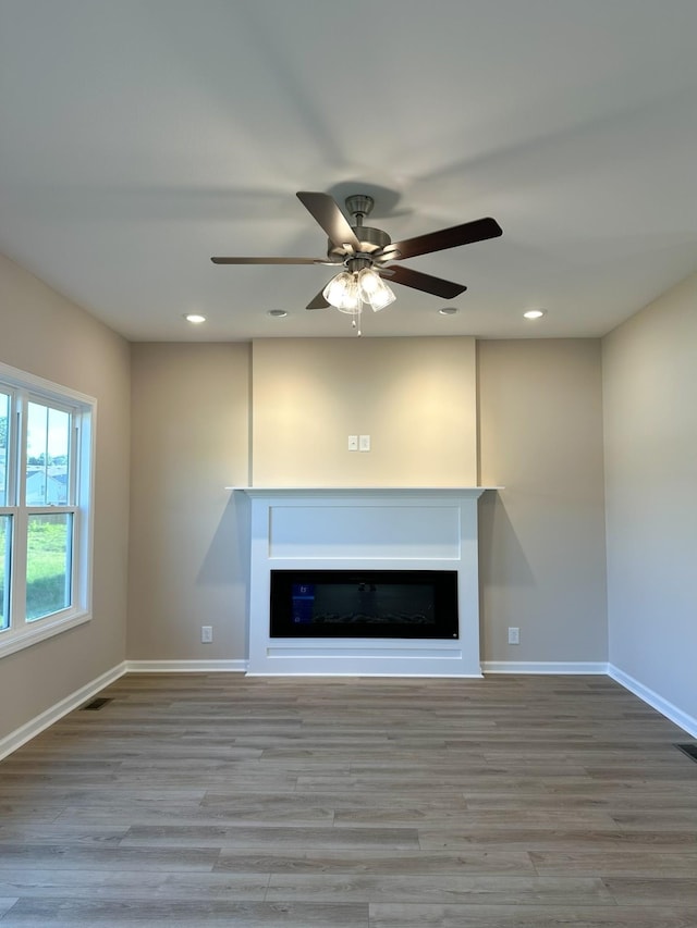 unfurnished living room with ceiling fan and light hardwood / wood-style floors