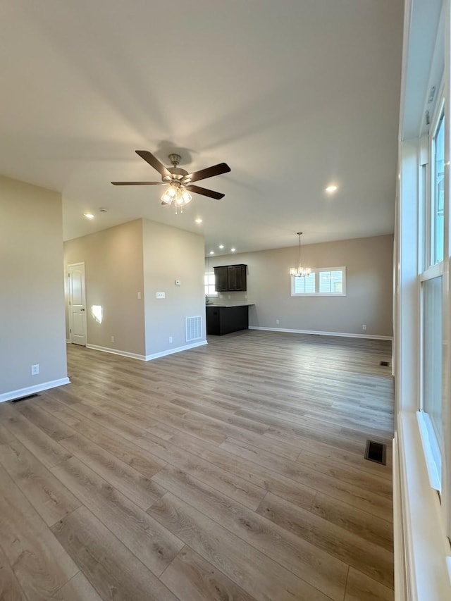 unfurnished living room with light hardwood / wood-style floors and ceiling fan with notable chandelier