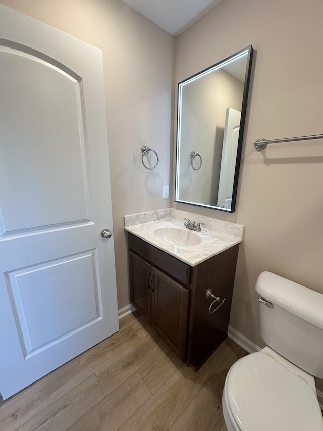 bathroom featuring vanity, wood-type flooring, and toilet