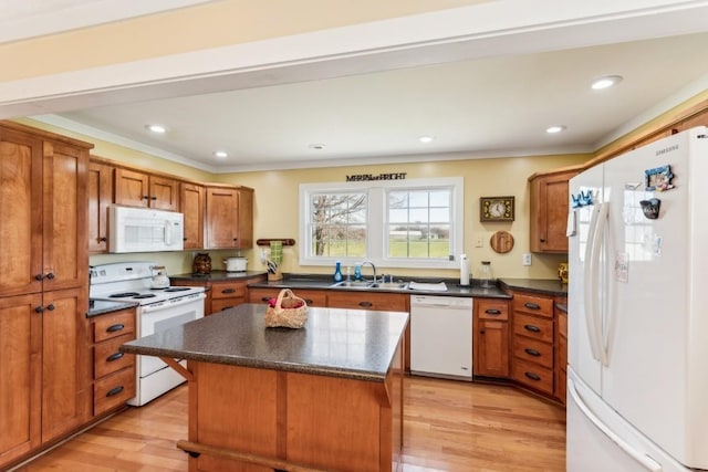 kitchen with sink, light hardwood / wood-style flooring, crown molding, white appliances, and a kitchen island