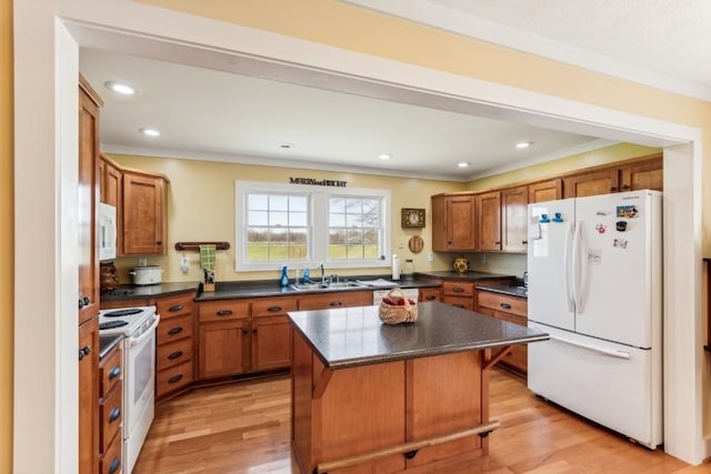 kitchen featuring a kitchen bar, white appliances, crown molding, sink, and a kitchen island