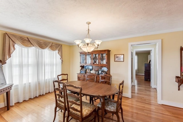 dining room with crown molding, light hardwood / wood-style flooring, a chandelier, and a textured ceiling