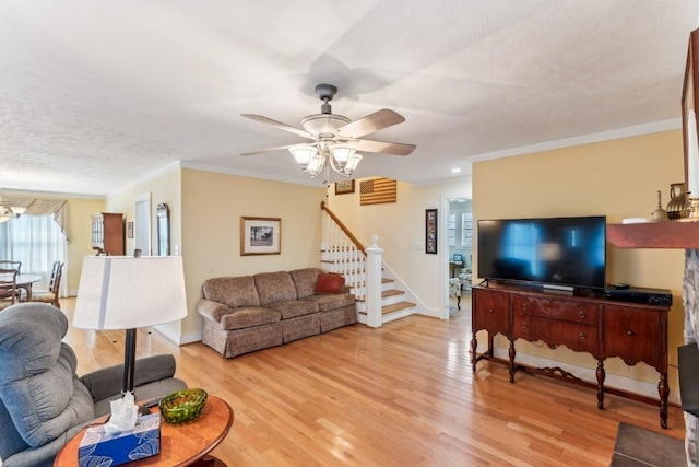 living room with ceiling fan, light hardwood / wood-style floors, a textured ceiling, and ornamental molding