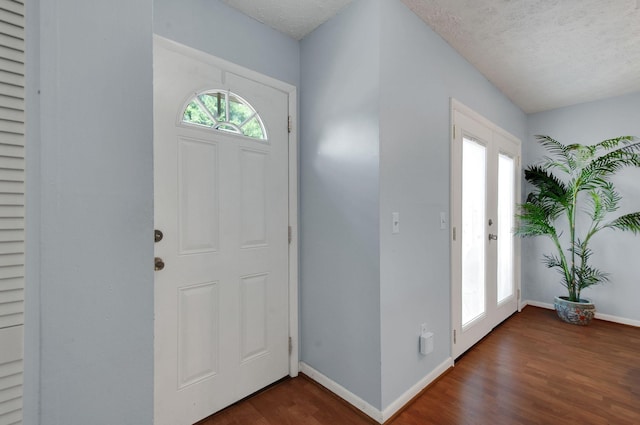 foyer with french doors, dark hardwood / wood-style flooring, and a textured ceiling