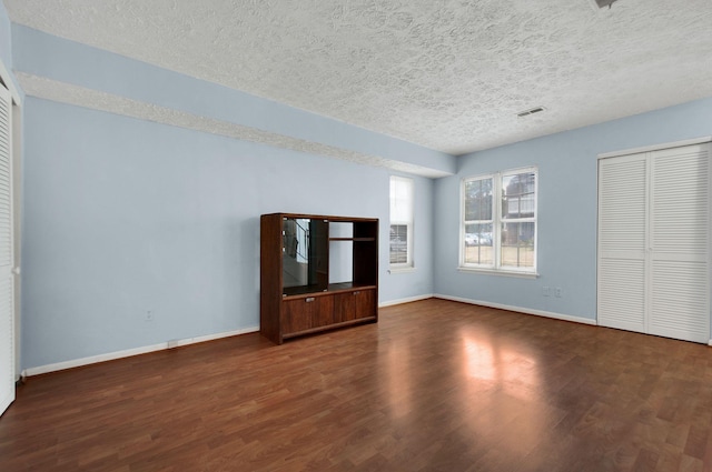 unfurnished living room featuring a textured ceiling and dark hardwood / wood-style floors