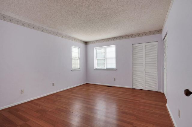 unfurnished bedroom with multiple closets, a textured ceiling, and hardwood / wood-style flooring