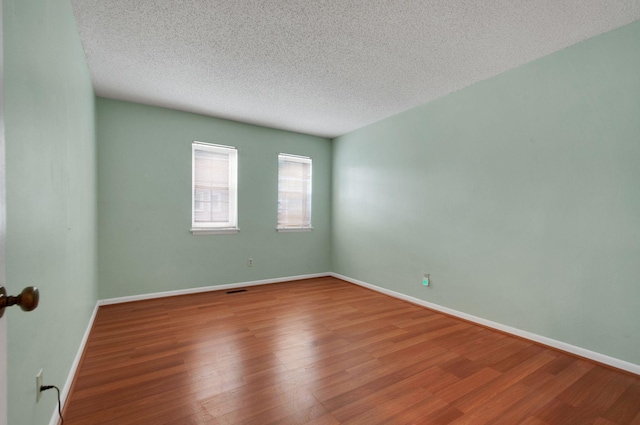 empty room with hardwood / wood-style flooring and a textured ceiling