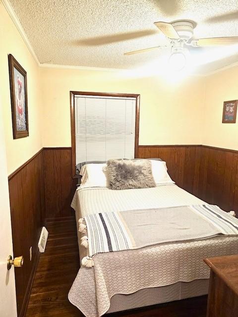 bedroom with a textured ceiling, dark wood-type flooring, ceiling fan, and ornamental molding