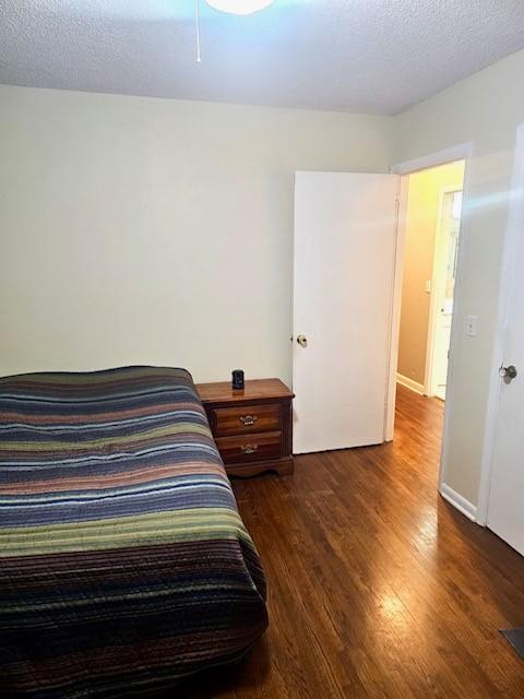 bedroom with dark hardwood / wood-style flooring and a textured ceiling