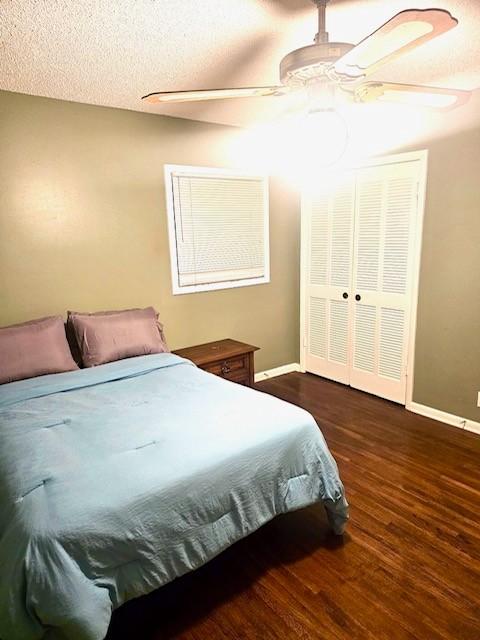 bedroom with a textured ceiling, a closet, ceiling fan, and dark wood-type flooring