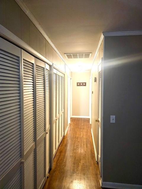 corridor with wood-type flooring and ornamental molding