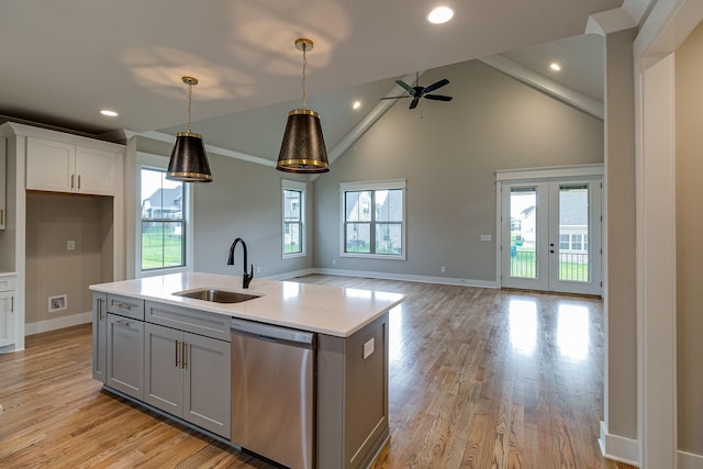 kitchen with french doors, sink, dishwasher, hanging light fixtures, and an island with sink