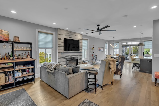 living room with a fireplace, light hardwood / wood-style floors, and ceiling fan