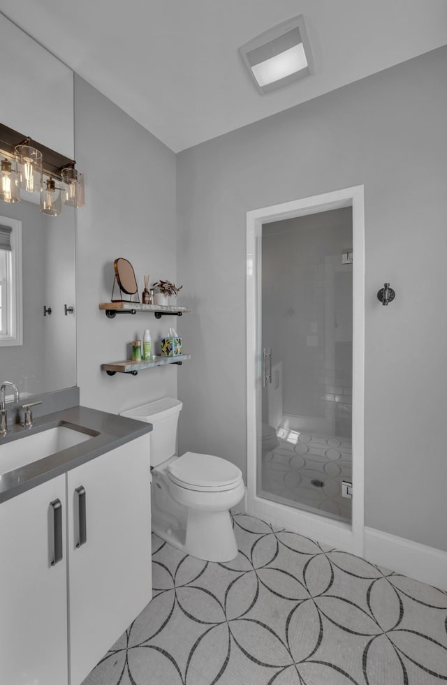 bathroom with an enclosed shower, vanity, toilet, and tile patterned flooring