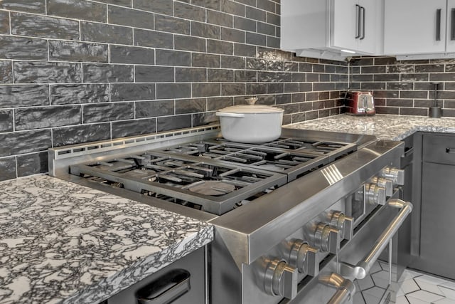 kitchen featuring range with two ovens, decorative backsplash, gray cabinets, light stone countertops, and white cabinetry