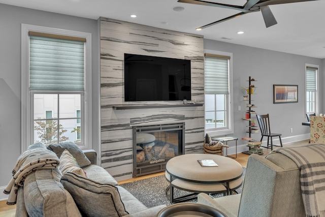 living room featuring light hardwood / wood-style flooring, ceiling fan, and a premium fireplace