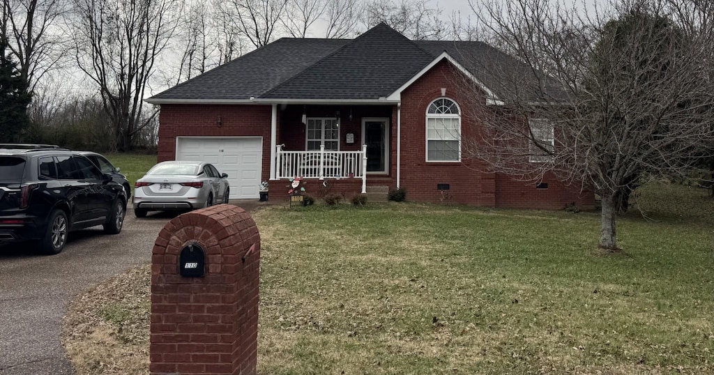 single story home with a front yard, a porch, and a garage