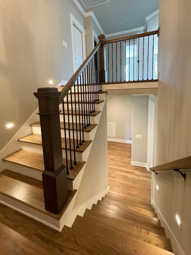 staircase with crown molding and hardwood / wood-style flooring